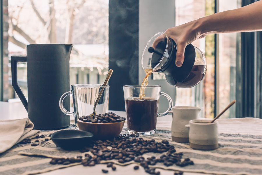 Hands holding a ceramic coffee cup near a window